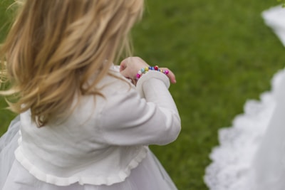 girl wearing white dress holding her bracelet