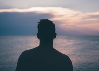 silhouette photography of man standing near sea