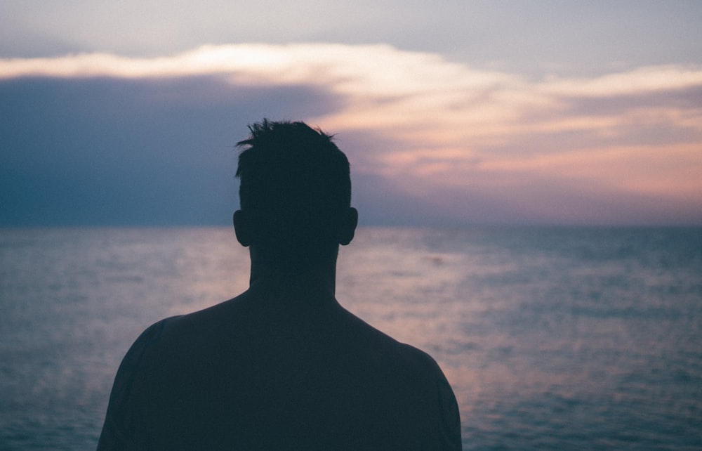 silhouette photography of man standing near sea