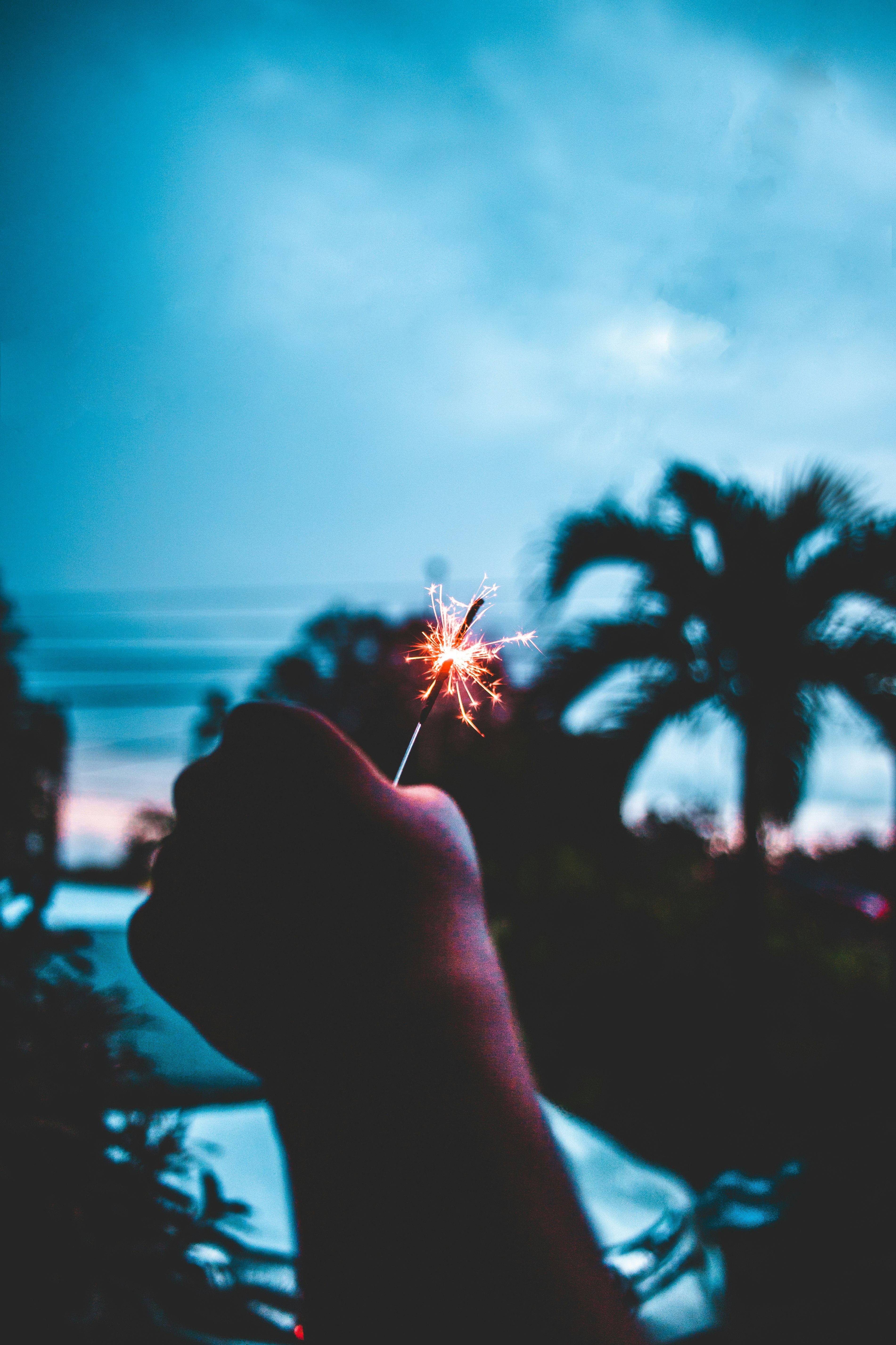 A person holding a lit sparkler in the air.