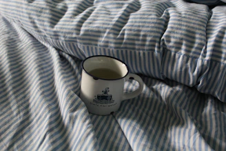 A stylish navy cap and a ceramic mug with Arctic Market’s maritime-inspired logo on a clean white surface.