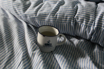 A stylish navy cap and a ceramic mug with Arctic Market’s maritime-inspired logo on a clean white surface.