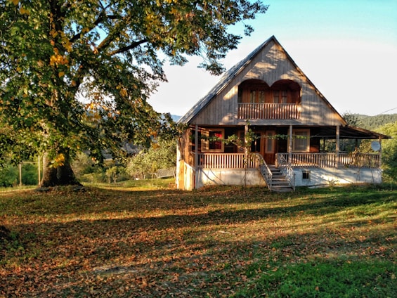 Spacious wooden family home with a wraparound deck and lush green lawn under soft afternoon light.