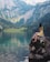woman sitting on rock near lake