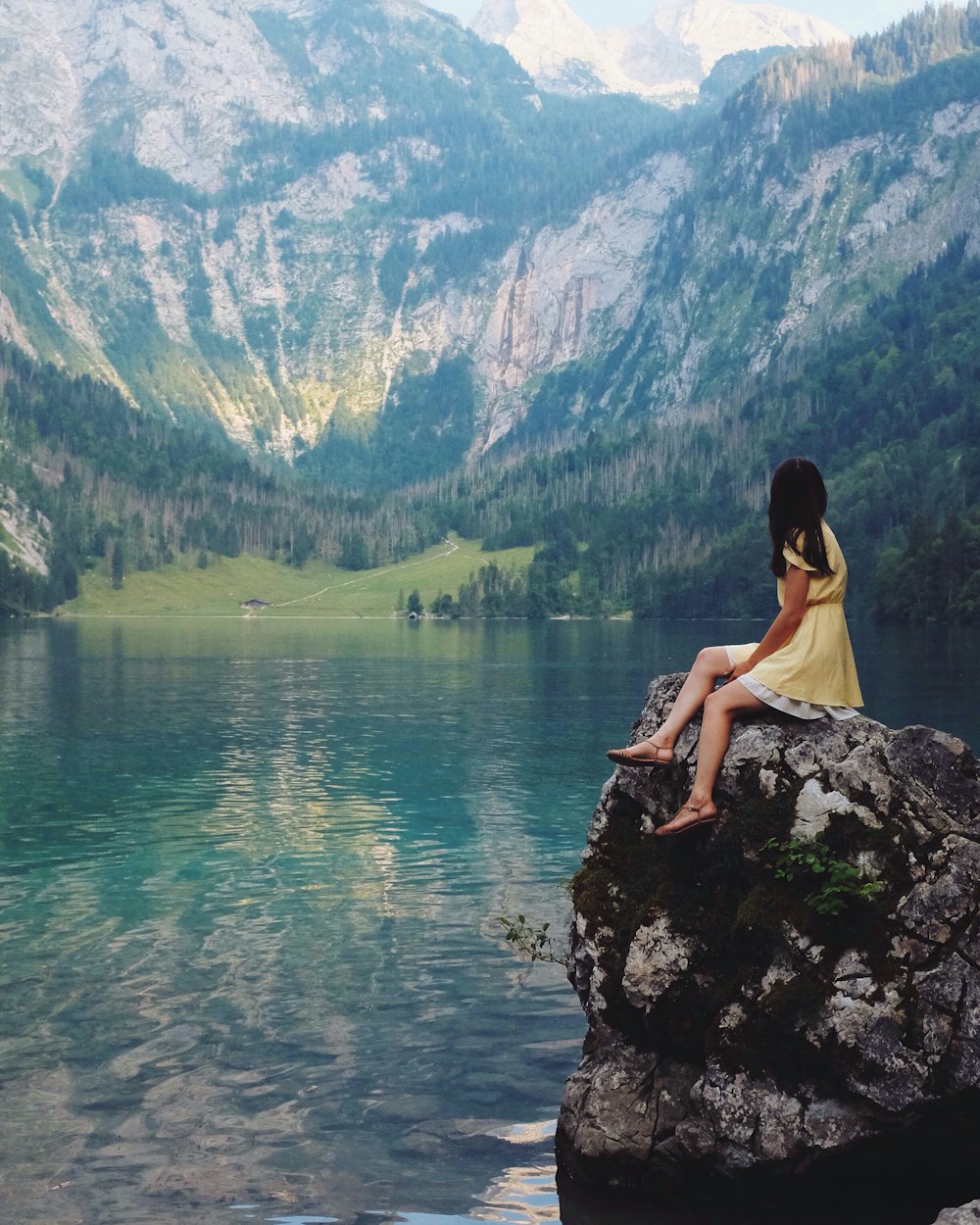 호수 근처 바위에 앉아있는 여자