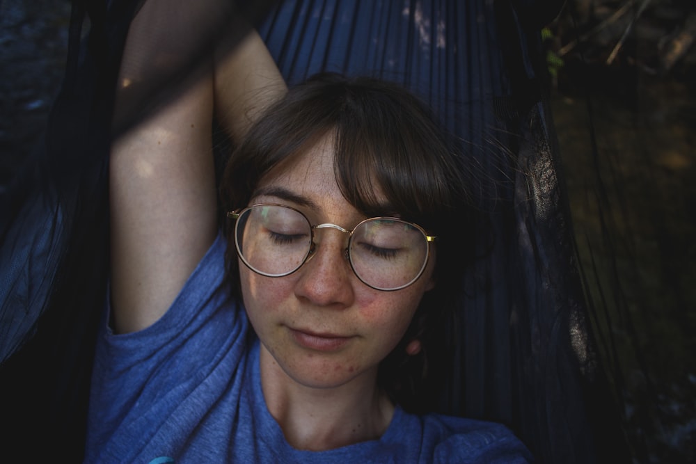 woman in blue crew-neck T-shirt laying on black hammock
