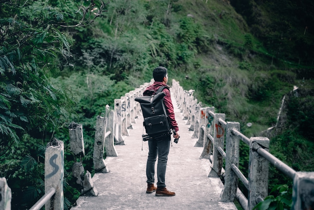 man standing on gray concrete bridge taken at daytime