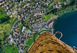 person riding hot air balloon taking photo of village near sea during daytime