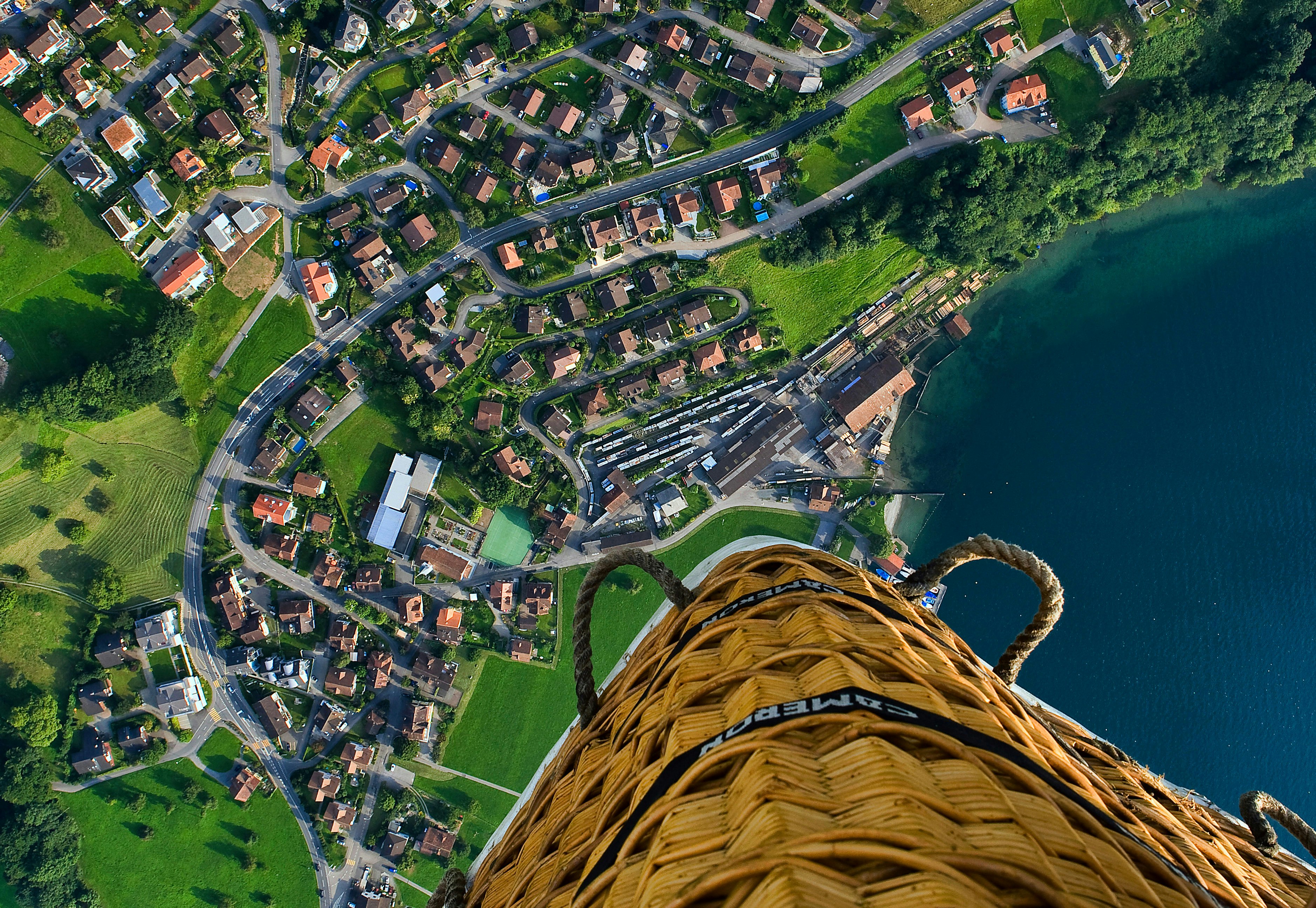 person riding hot air balloon taking photo of village near sea during daytime