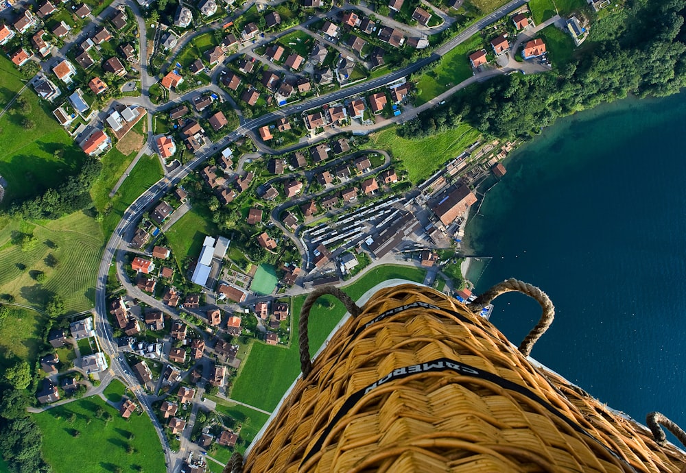 Person, die mit einem Heißluftballon fährt und tagsüber ein Foto eines Dorfes in der Nähe des Meeres macht