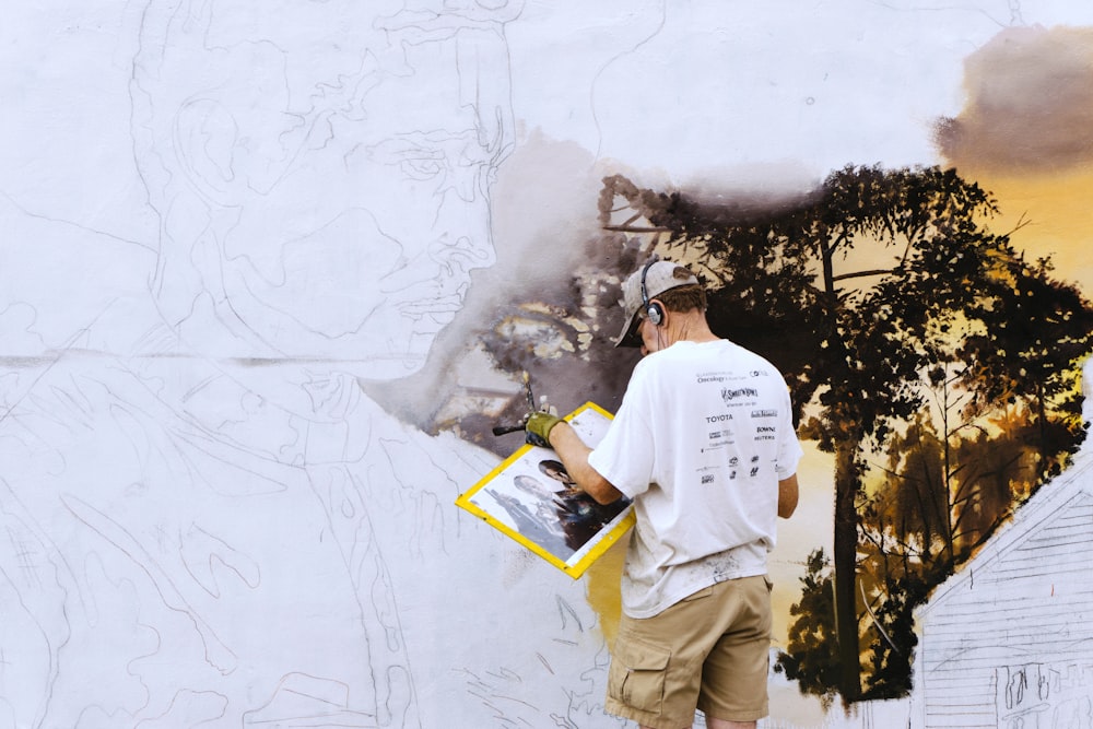 man wearing black headphones near white wall paint