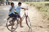 two boy riding on red step-through bicycle during daytime