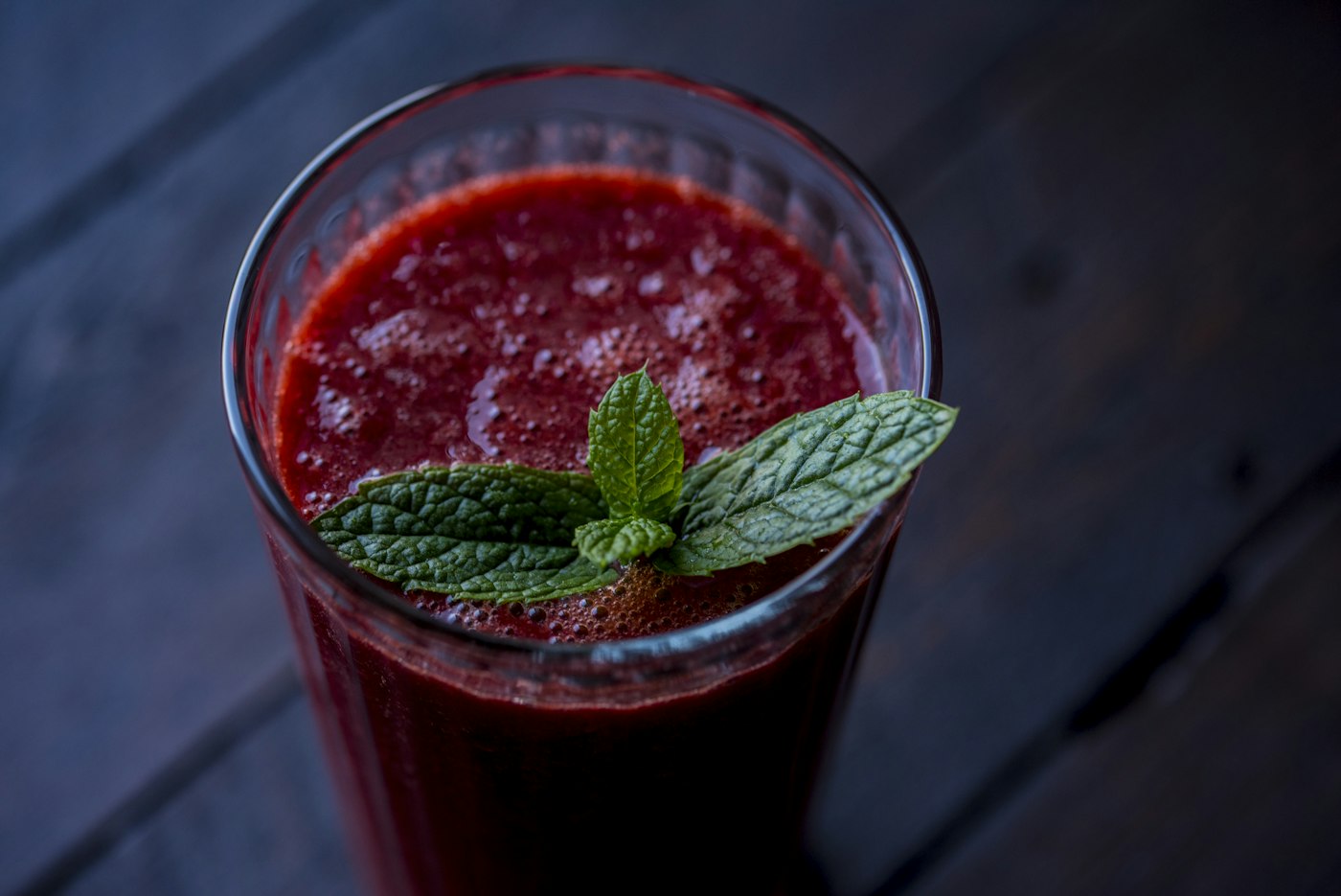 A glass of deep red beetroot juice topped with fresh mint