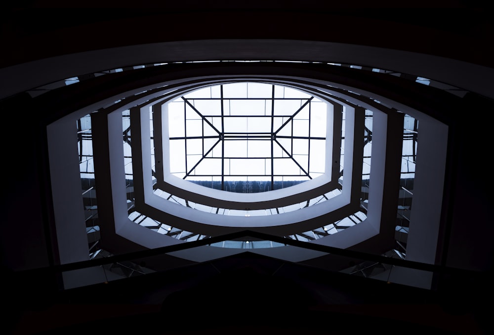 Photographie en contre-plongée de l’intérieur d’un bâtiment blanc avec un toit en verre transparent pendant la journée