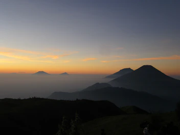 An artistic video still showing dynamic clouds shifting over mountain peaks at dawn.