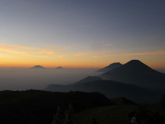An artistic video still showing dynamic clouds shifting over mountain peaks at dawn.