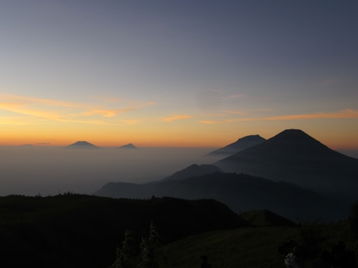 A serene Idaho mountain landscape at dawn with soft peacock blue sky hues.