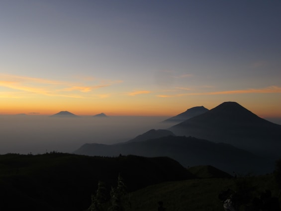 A serene sunrise over the snow-capped peaks of the Himalayas with pilgrims walking a mountain trail.