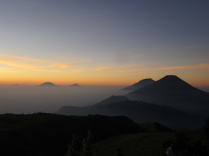 A serene mountain trail where a lone hiker enjoys the sunrise over misty peaks.