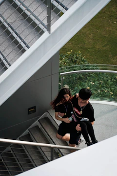 Two movers carefully carrying a refrigerator down a staircase.
