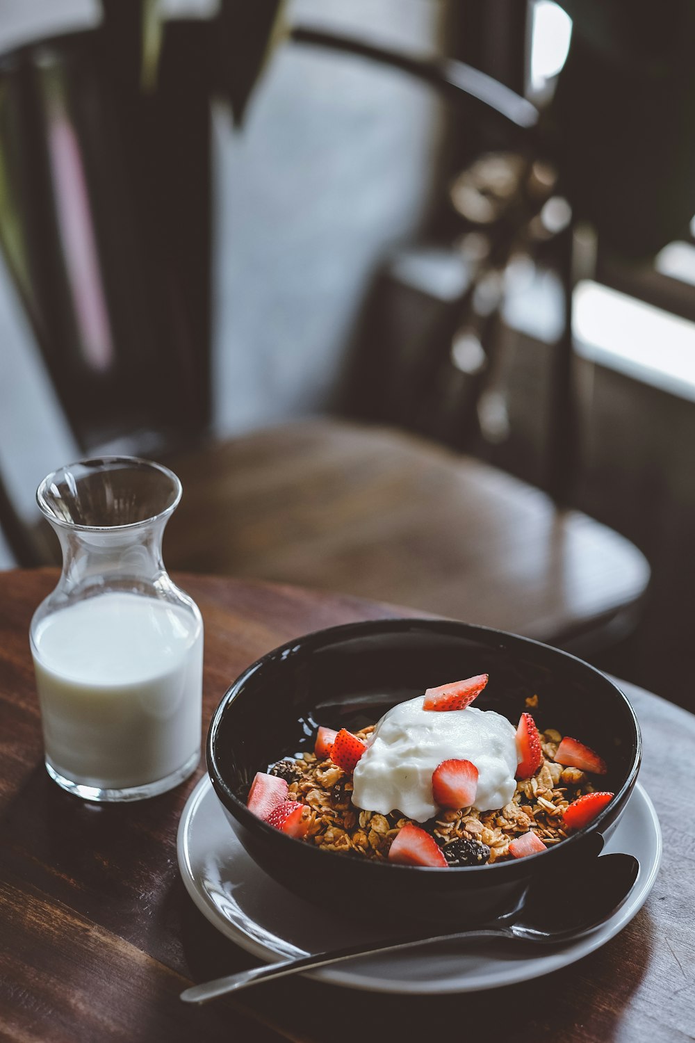 Tazón de cereal con fresas junto a un vaso de leche en la mesa