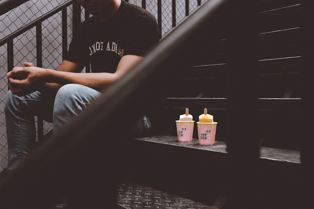 person sitting on stair with two disposable cups