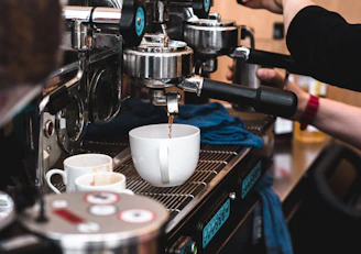 Barista training session showing hands preparing espresso shots on the Alcantara machine.