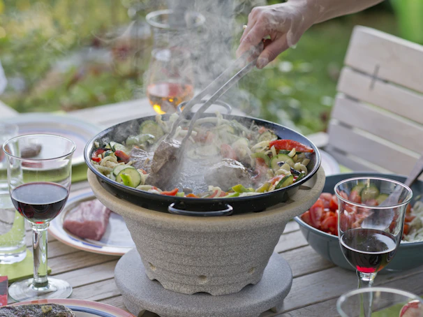 A lively outdoor barbecue gathering with friends sharing food served on elegant wooden boards