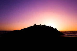 Sunset view from the peak of Mount Teide with hikers silhouetted against a colorful sky.