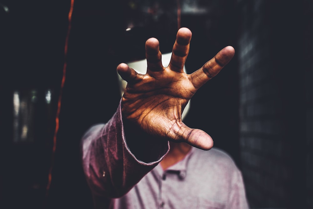 selective focus photography of man raising his right hand during daytime