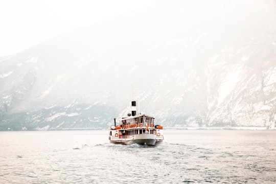 white and black ship on calm body of water near mountain in Lake Garda Italy