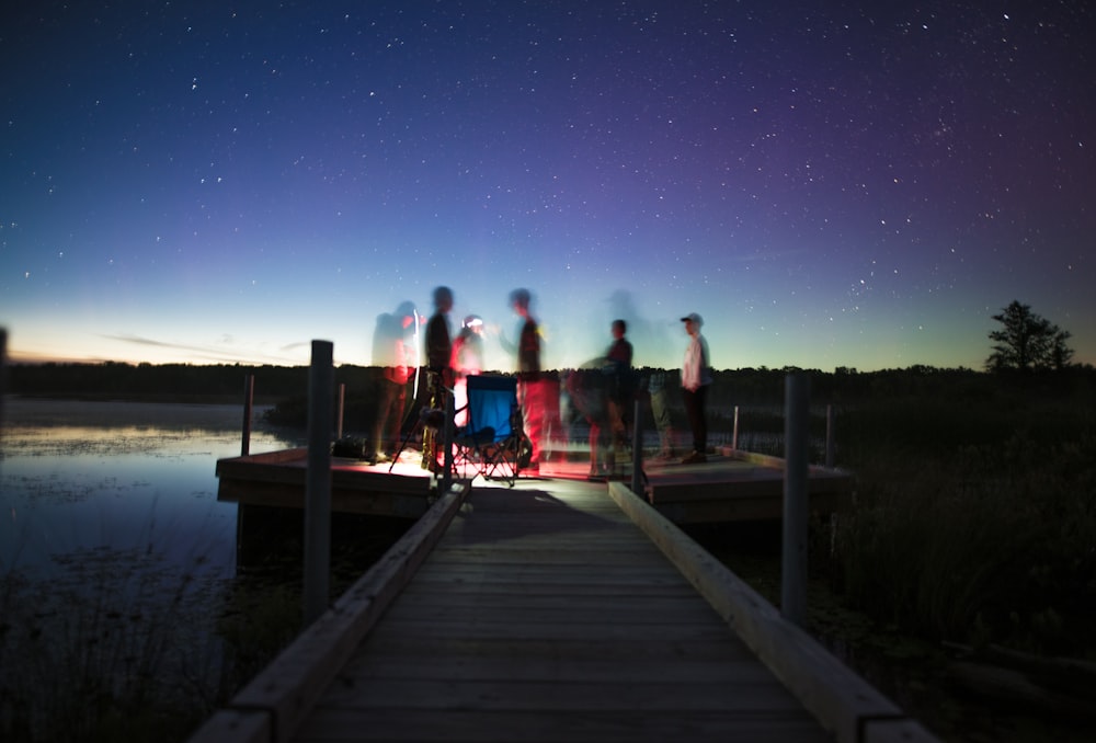 person illustration on brown wooden dock stage photography during nightime