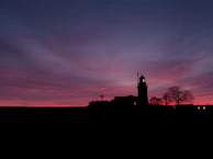 A lighthouse silhouette against a twilight sky, symbolizing guidance and dreams.