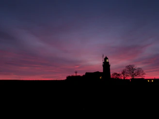 A lighthouse silhouette against a twilight sky, symbolizing guidance and dreams.