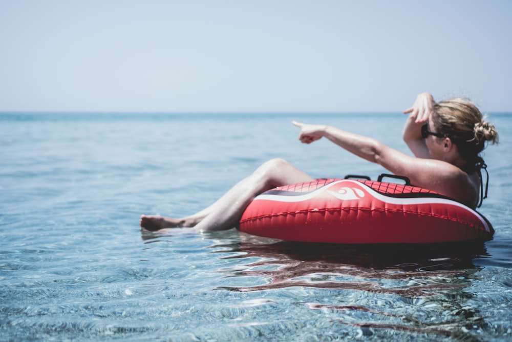 Frau auf einem aufblasbaren Schwimmer im Ozean zeigt mit einem Finger auf Posidi