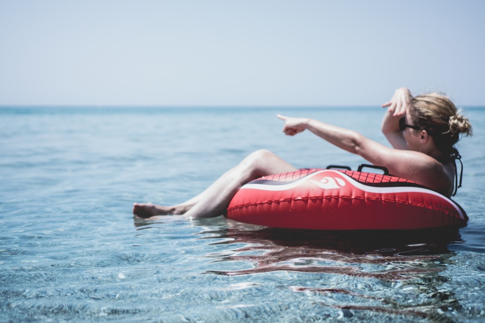 Mulher em um flutuador inflável no oceano apontando com um dedo para Posidi