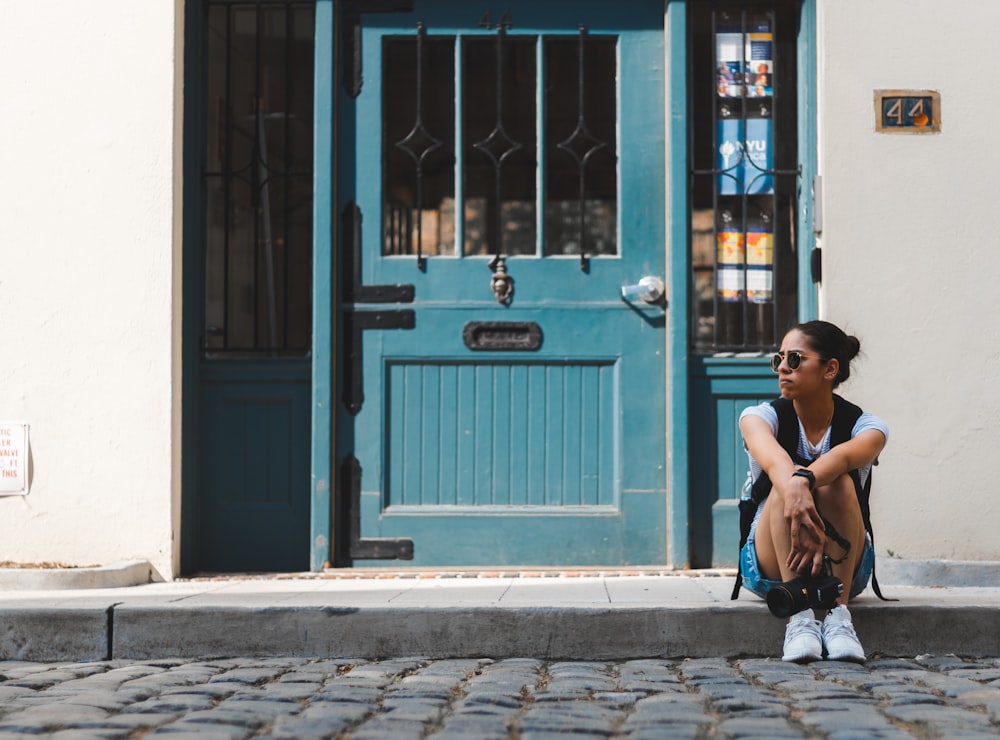 Mujer sentada cerca de la puerta azul