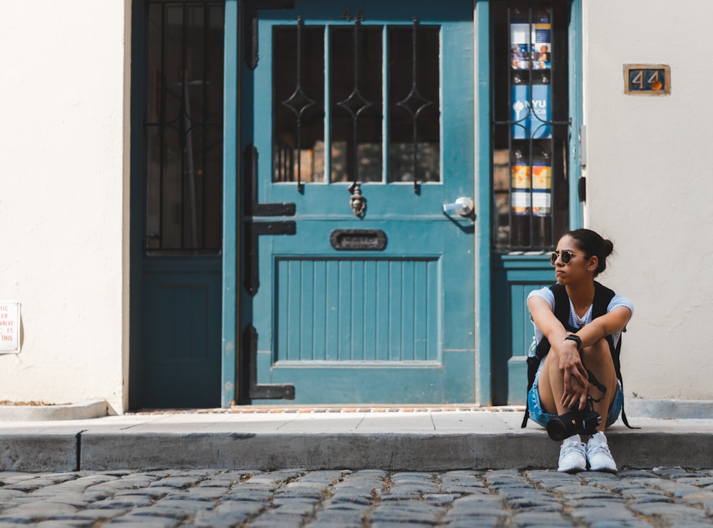 woman sitting near blue door