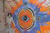 A colorful canvas with chaotic, playful patterns and a central eye motif glowing in neon hues.