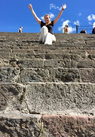 A joyful traveler standing atop Petra’s ancient stone steps at sunset, soaking in the golden hues.