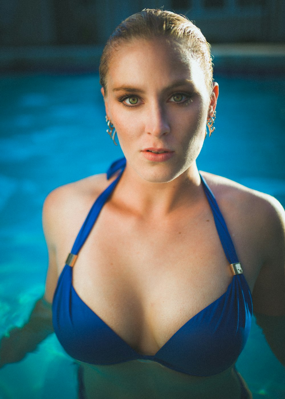 Mujer en top de bikini de tira azul en piscina mirando recta