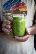person holding a glass mason mug filled with smoothie