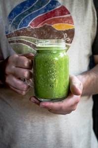 person holding a glass mason mug filled with smoothie