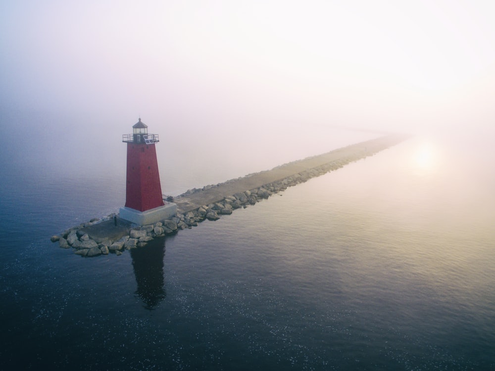 red lighthouse on gray dock at daytime