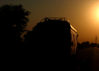 A modern bus driving along a scenic highway at sunset.