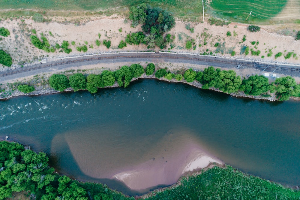 Photographie aérienne d’une route au bord d’un plan d’eau entouré d’arbres