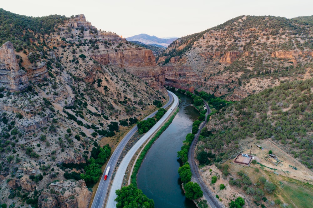 aerial photo of road between river and mountain during daytime