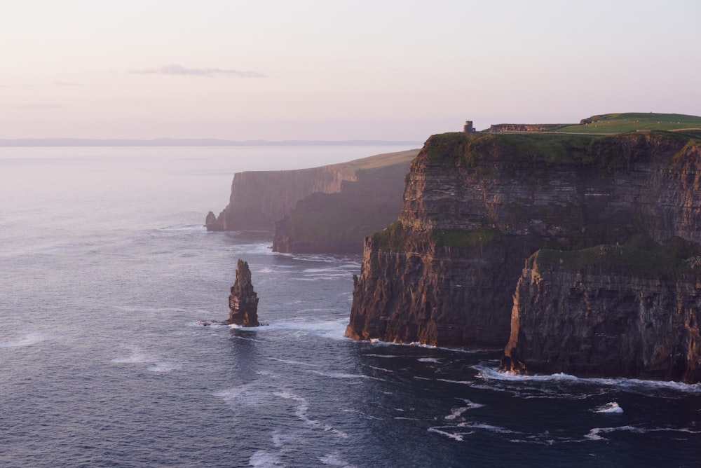 rock formation near sea under white sky