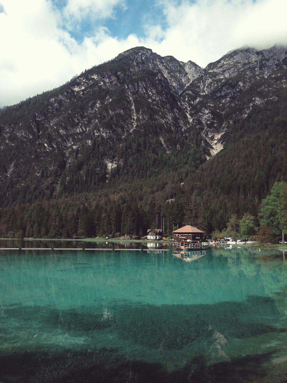 brown wooden gazebo beside mountain and body of water