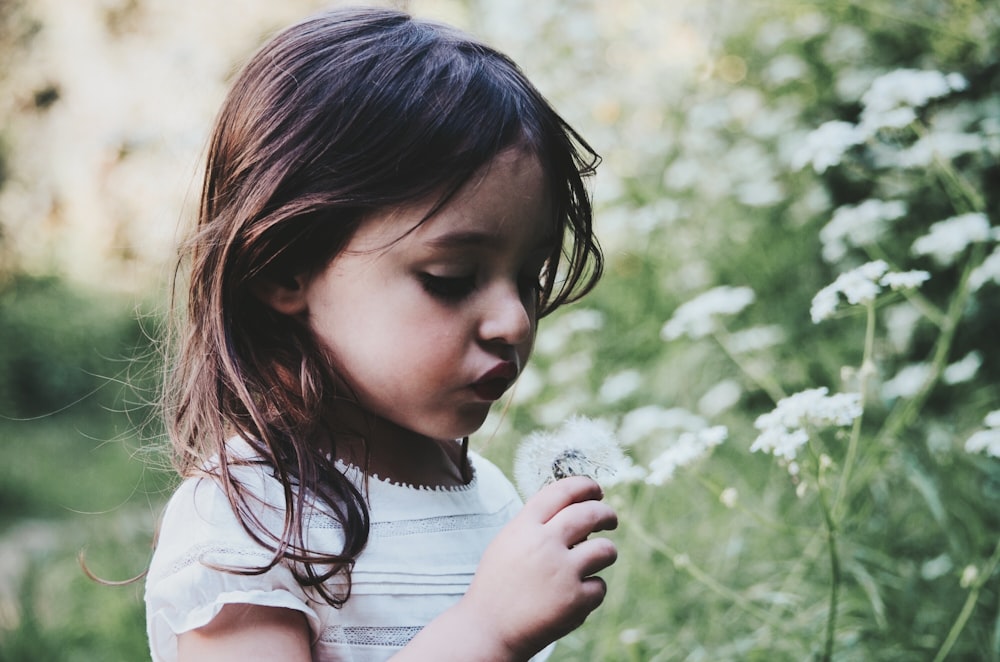 menina segurando a flor branca durante o dia
